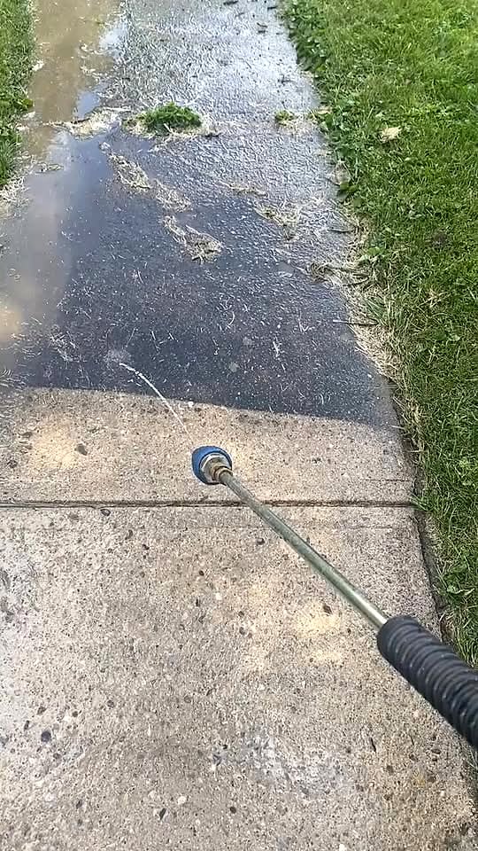 Pressure washing a concrete path, half cleaned